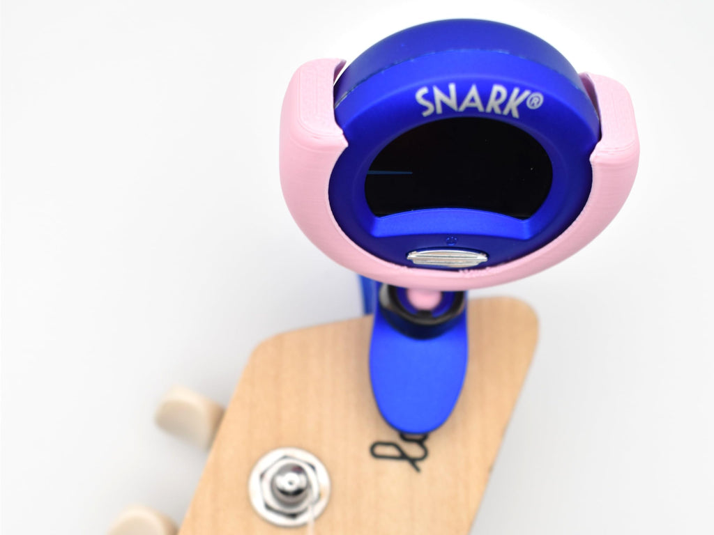 A closeup view of a 3D-printed holder attached to a Snark tuner and clipped onto the neck of a guitar.